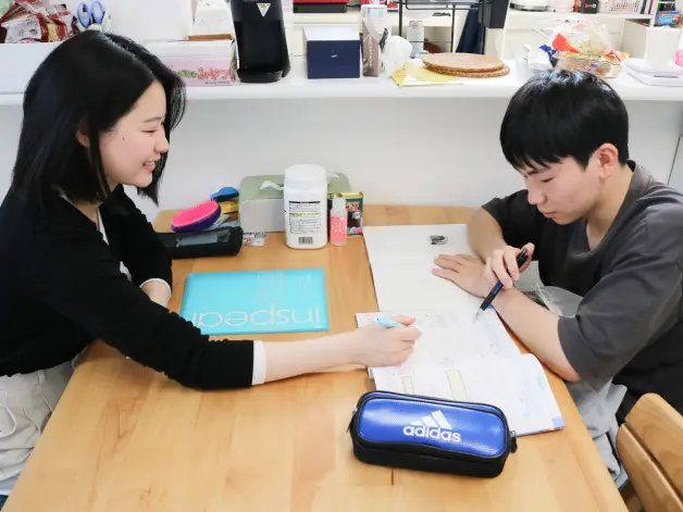 写真：ゆいとくんが机に向かって家庭教師と勉強している